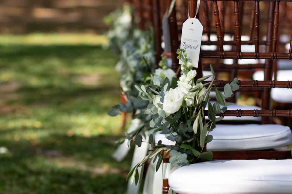 Florals adorn guest chairs for ceremony